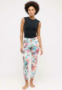 Body nero senza maniche, abbinato a pantaloni stampati floreali colorati in tonalità di rosa, blu e verde. I pantaloni presentano bottoni frontali.