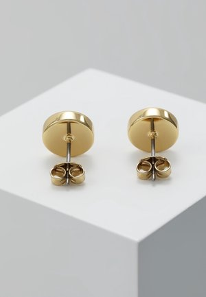 Paar runde goldene Steckerohrringe mit Schmetterlingsverschlüssen auf weißer Eckfläche präsentiert.