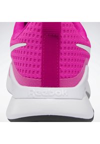 Talons de chaussure de sport rose vif avec semelle blanche, tige en tissu mesh, languette à tirer et logo "Reebok" embossé sur la semelle intermédiaire.