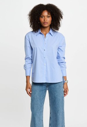 Hellblaues Hemd mit vertikalen weißen Streifen, langärmlig und mit klassischem Kragen, kombiniert mit weiten Jeans.