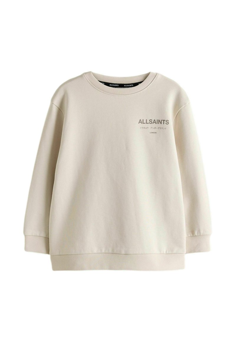 Sweat-shirt de couleur crème en tissu doux, avec un col rond, des manches longues et un logo imprimé sur le devant.