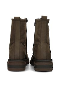 Bottines en cuir brun avec une texture lisse, des fermetures éclair sur le côté et une semelle empilée avec des rayures sombres contrastantes.