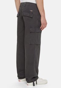 Cargo byxor i mörkgrå bomullstyg, med stora sidofickor och en avslappnad passform. Förstärkt sömnad längs sömmarna och logotypetikett på midjebandet.
