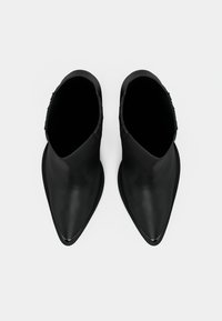 Melnas ādas potītes zābaki ar smailu purngalu un gludu tekstūru. Piedāvā slaidu siluetu un minimālistisku apdari sānos.