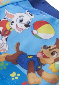 Tessuto blu con cani dei cartoni animati giocosi, uno con macchie e un gilet rosso, l'altro marrone con una divisa blu, su uno sfondo vivace.