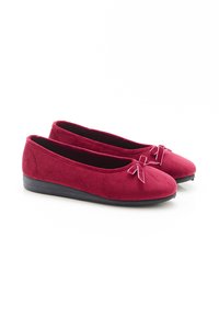 Ballerine in suede rosso con punta rotonda e un piccolo fiocco decorativo nella parte anteriore. Suola in gomma nera con minima elevazione.
