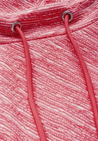 Röd texturerad hoodie med vita ränder, med en dragsko som träs genom silverfärgade öglor. Slät tyg med en mjuk känsla.