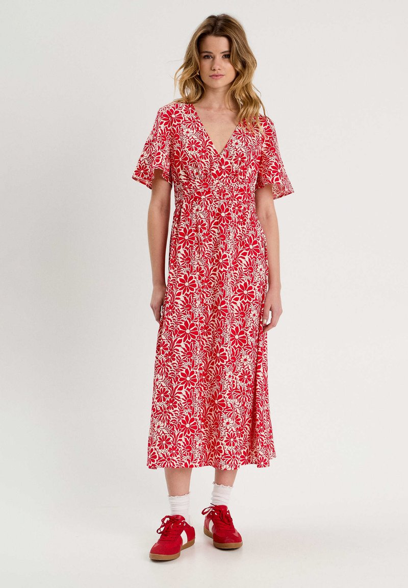 Robe portefeuille rouge à fleurs avec des manches courtes volantées, dotée d'un décolleté en V, d'une taille cintrée et d'une jupe fluide arrivant mi-mollet.
