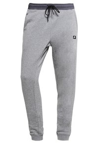 Šedé tepláky s elastickým pasem, šňůrkou a černou logu; zúžený střih nohavic a měkká, strukturovaná tkanina.