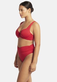 Rotes Bikini-Set mit einem geformten, wattierten Oberteil mit breiten Trägern und einem hochgeschnittenen Unterteil mit gerafften Details. Glattes, dehnbares Material.