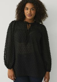 Zwart doorschijnend blouse met een gestructureerde stof, voorzien van een knoopsluiting bij de hals, pofmouwen en een losse pasvorm, gedetailleerd met een subtiel ruitpatroon.