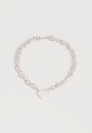 Silver chain necklace with circular links and a heart-shaped pendant engraved with the word "STOLEN" on a plain background.