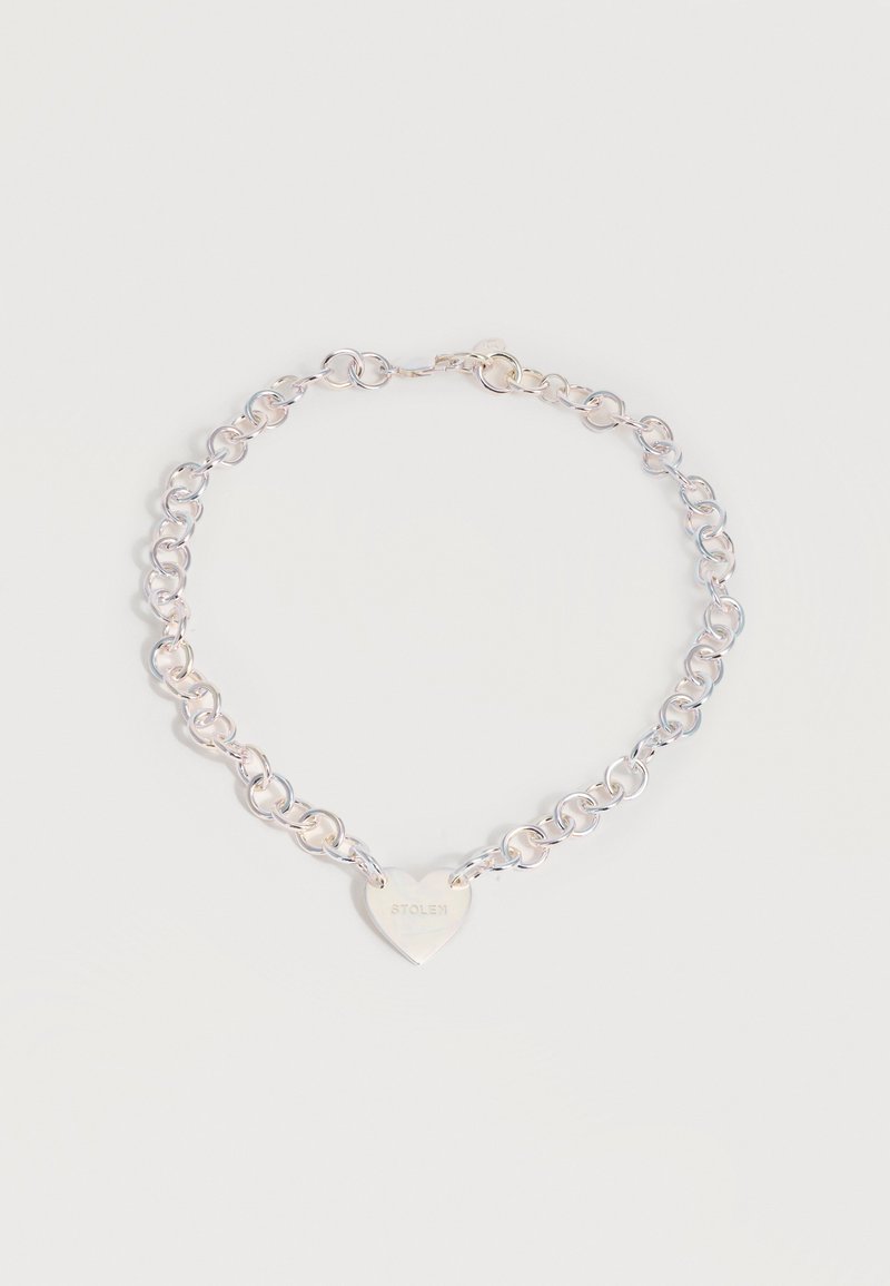 Ασημένιο κολιέ με κυκλικούς κρίκους και καρδιόσχημο μενταγιόν χαραγμένο με τη λέξη "STOLEN" σε απλό φόντο.