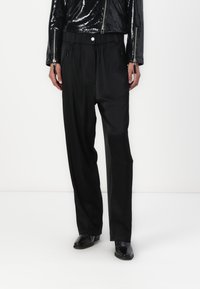 Pantalons larges noirs en tissu lisse, dotés d'une taille élastique, de poches zippées et d'une coupe décontractée pour un confort optimal.