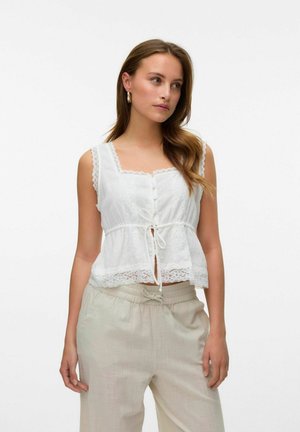 White sleeveless top with lace trim, button closures, and tie waist detail. Paired with light-colored, loose-fitting pants.