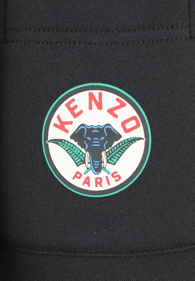 Tissu noir avec un logo circulaire KENZO Paris en rouge et vert, représentant un éléphant entouré de feuilles de palmier, bordé de blanc et de vert.