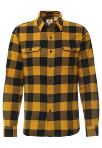 Camicia in flanella gialla e nera con un classico motivo a quadri, con chiusura a bottoni sul davanti e due tasche sul petto. Realizzata in un tessuto morbido e texturizzato.