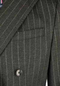 Donkergrijze pinstripe colbert met notch lapel, paspelzak en enkele donkere knopen sluiting.