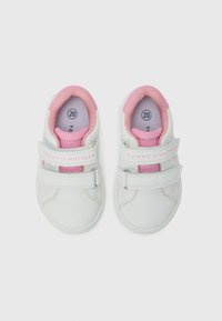 Baskets blanches avec des accents roses, dotées d'une sangle à boucle, d'un col rembourré et d'un logo sur la sangle. Taille 20 indiquée à l'intérieur.