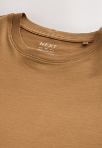 Brązowy t-shirt z okrągłym dekoltem, z nadrukowaną wewnętrzną metką pokazującą rozmiar medium oraz oznaczeniem regular fit.