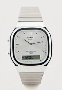 Ασημένιο ρολόι Casio quartz με ορθογώνιο καντράν, αναλογικές και ψηφιακές ενδείξεις, μπρασελέ από ανοξείδωτο ατσάλι και σήμανση αντοχής στο νερό.