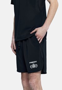 Bermudas deportivas negras con cintura elástica, bolsillos laterales y la marca blanca "FREDDY elite" en la parte inferior de la pierna. Fabricación ligera y suave.