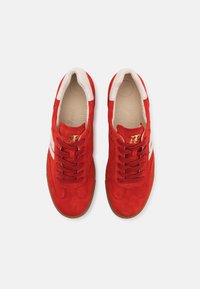 Baskets en daim rouge avec touches blanches, bout arrondi, design à lacets et semelle extérieure en caoutchouc gomme texturée. Intérieur doté d'un rembourrage doux.