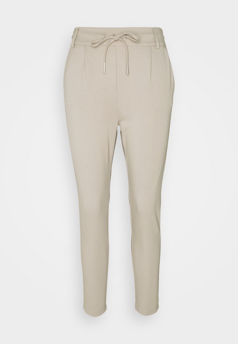 Pantalon beige effilé avec taille à cordon, deux plis à l'avant et texture lisse. Design simple sans motifs ni accents visibles.