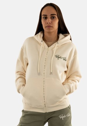 Crème hoodie met rits, voorzien van een trekkoordhuood, voorzakken en geborduurde tekst. Heeft een zachte textuur en ribbelboorden.