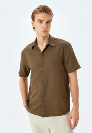 Camisa de botones marrón de manga corta con cuello, hecha de tejido texturizado. Presenta cinco botones en la parte delantera y un diseño de corte relajado.