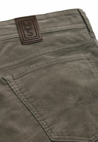 Olive green corduroy pants with a brown leather brand label. Features visible stitching and a back pocket with a piped edge.
