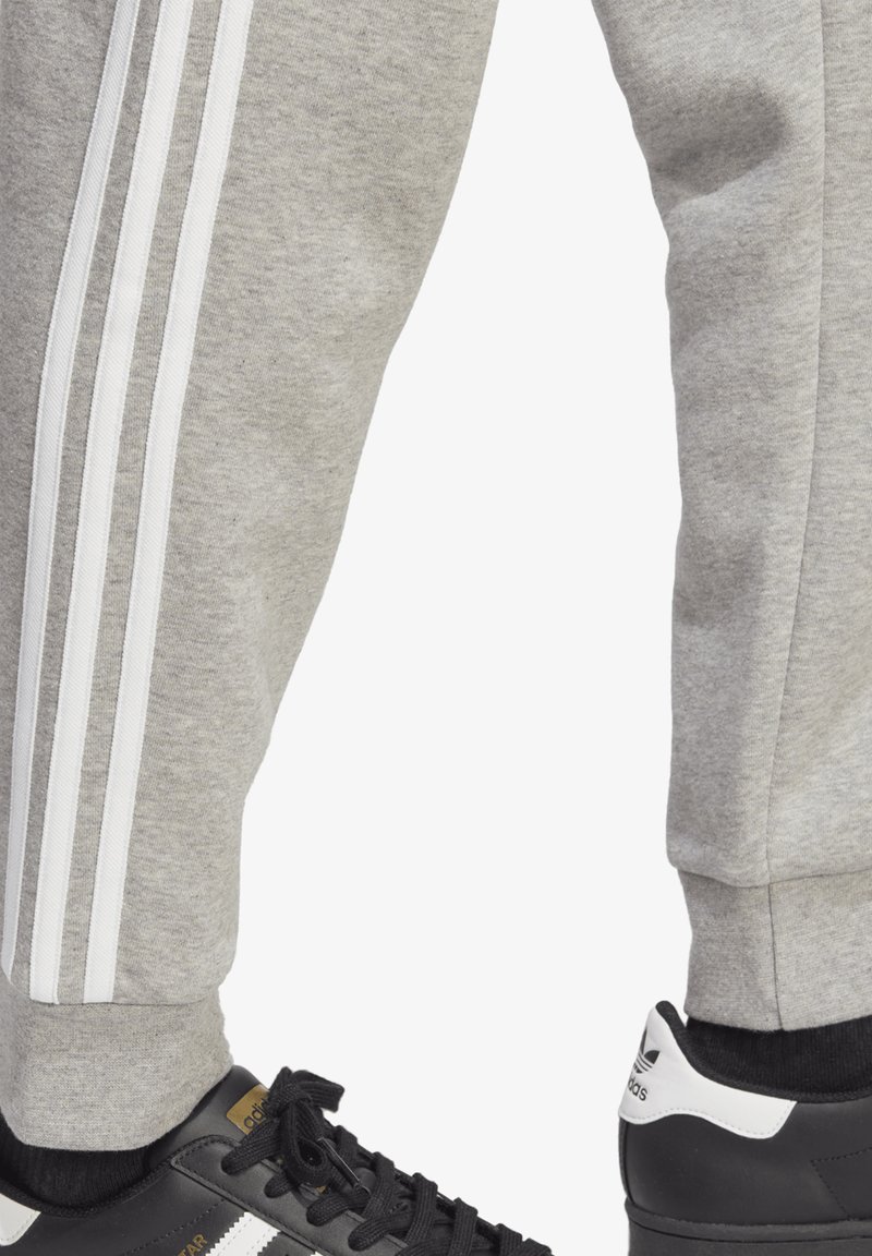 grey adidas joggers with black stripes