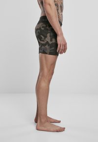 Shorts de bain en camouflage dans des tons de vert et de marron, dotés d'une taille élastique, d'une coupe ajustée et d'un tissu lisse et léger.