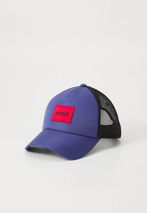 Purple cap with a solid front panel and black mesh back. Features a red rectangular patch displaying the word "HUGO" in black.