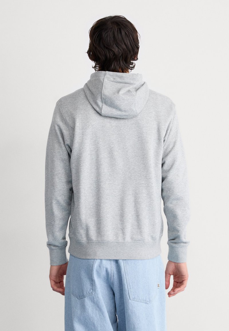 Sudadera gris con capucha ajustable, puños y banda de cintura acanalados. Fabricada con un tejido suave, cuenta con una textura lisa y un ajuste holgado.