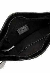 Interno di una borsa a tracolla in pelle nera, con chiusura a zip, rivestimento in tessuto morbido e tasca etichettata per l'organizzazione.