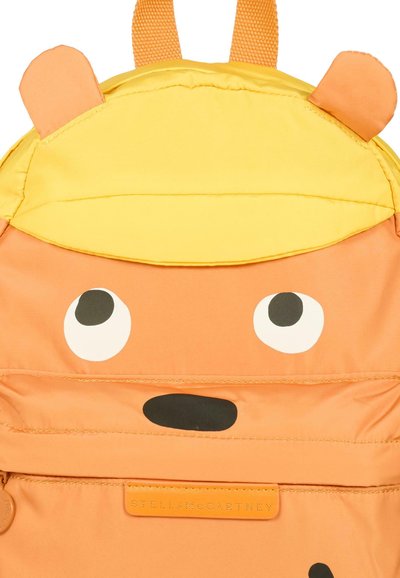 Sac à dos orange avec une casquette jaune, présentant de grands yeux blancs et un nez noir. Matériau durable avec des détails cousus et une étiquette de logo.