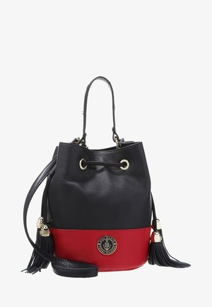 Petit sac seau en cuir noir et rouge avec fermeture par cordon, longue bandoulière, pompons et badge rond avec logo Tommy Hilfiger sur le devant.