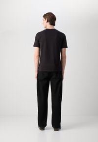Tricou negru cu mânecă scurtă dintr-o țesătură moale, asortat cu pantaloni negri largi. Design simplu, detalii minime și siluetă dreptă.
