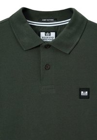 Tmavě zelená polokošile s límečkem na knoflíky, malou nášivkou loga "Weekend Offender" na hrudi a vnitřní etiketou s nápisem "Admit Nothing."