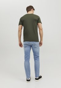Mørkegrøn kortærmet skjorte kombineret med lyseblå jeans. Casual pasform med rund halsudskæring og klassisk denimstil på jeans.