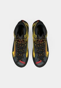 Sapatilhas altas em materiais amarelo, cinza e preto. Apresentam atacadores coloridos, um cabedal texturizado e um design em padrões. Área do bico reforçada.