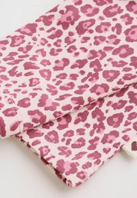 Rosa tyg med mörkrosa leopardmönster vikt mot en vit bakgrund.