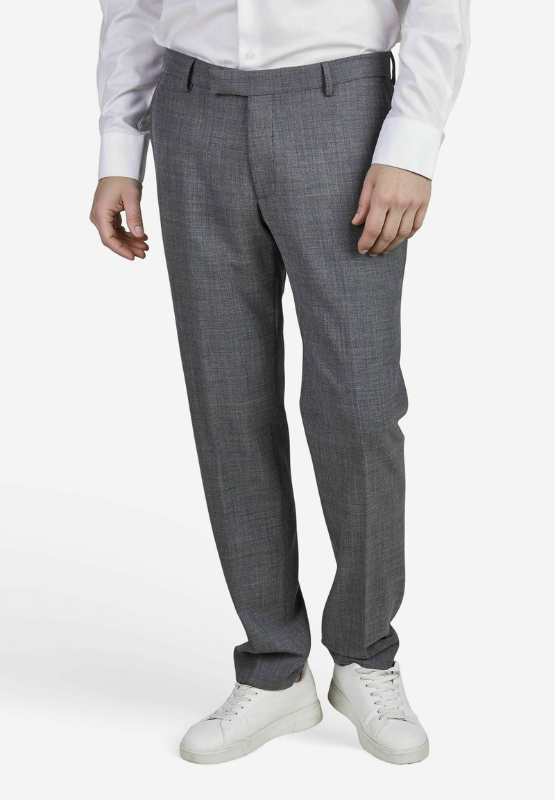 Pantalons à carreaux gris en tissu tissé, avec une coupe droite et une taille standard. Associés à des baskets blanches.