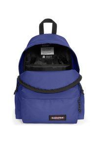 Fialový látkový batoh se zipovou přední kapsou, kulatým vrchem a černým zipem. Obsahuje štítek uvnitř s pokyny k péči.