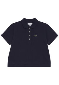 Tummansininen polo-paita, joka on valmistettu puuvillasta. Paitassa on klassinen kaulus, lyhyet hihat, viisimman napin lista ja brodeerattu vihreä logo.