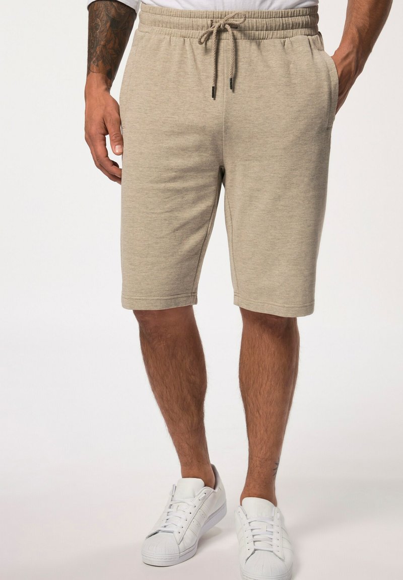 Shorts en coton mélangé beige avec une taille élastique, fermeture à cordon, poches latérales et une coupe droite, assortis à des baskets blanches.