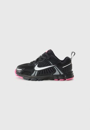 Musta ja pinkki Nike:n juoksukenkä, jossa valkoinen swoosh-logo, verkkokuviointi ja kantapään vetolenksu harmaalla taustalla.