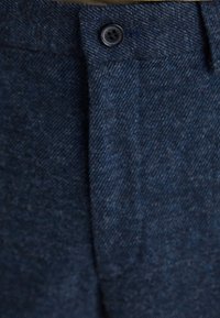 Pantaloni blu scuro realizzati in tessuto strutturato, dotati di chiusura con un solo bottone in vita e design con fronte piatto.