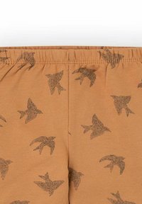Pantalones cortos de tela marrón con un patrón repetitivo de aves negras. Cintura elástica, textura suave y diseño ligero para mayor comodidad.